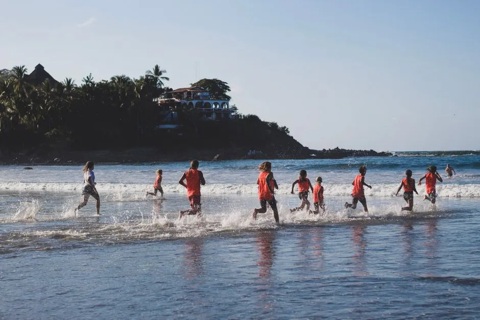 Groupe d'enfants courant et jouant dans les vagues sur une plage tropicale, ambiance vacances en famille