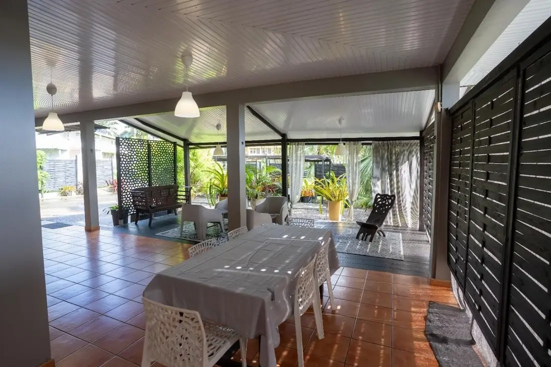 Varangue de la Casa Belas Artes : table couverte d’une nappe claire, fauteuils ajourés et jardin en arrière-plan