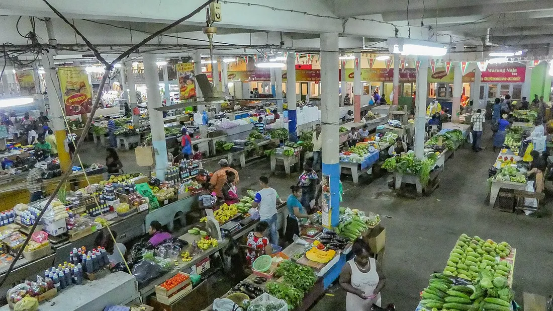 Étals de fruits et légumes et clients dans la halle du marché central de Paramaribo, au Suriname