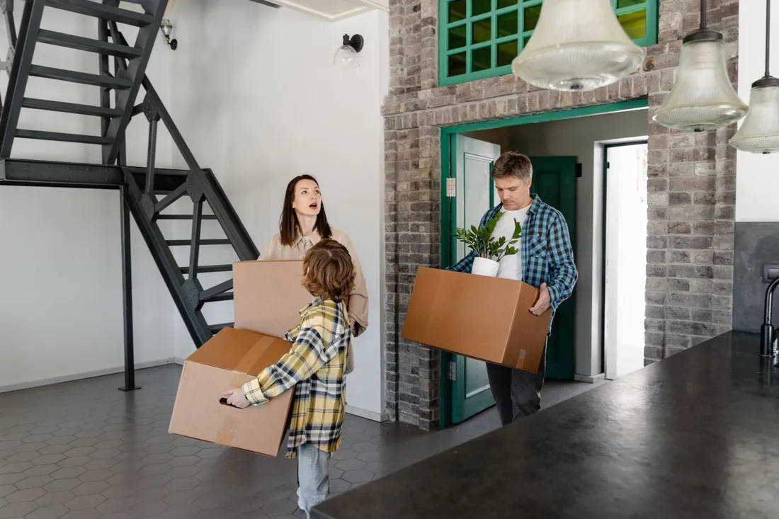 Famille portant des cartons de demenagement en entrant dans sa nouvelle maison