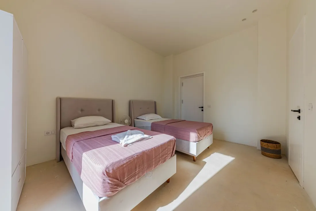 Chambre lumineuse d'un logement meublé équipée de deux lits simples et de serviettes pliées, adaptée à l'hébergement de staff et de prestataires