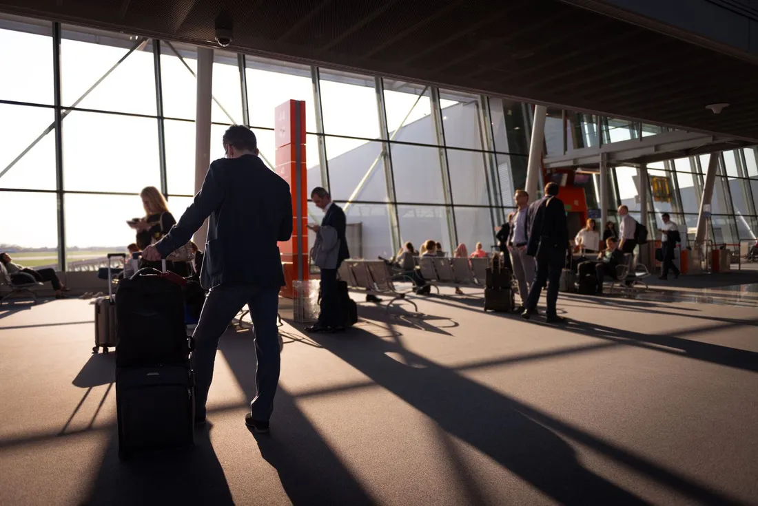 Professionnels en deplacement avec bagages dans un terminal, illustrant les intervenants en mission ou formation ayant besoin d'un hebergement