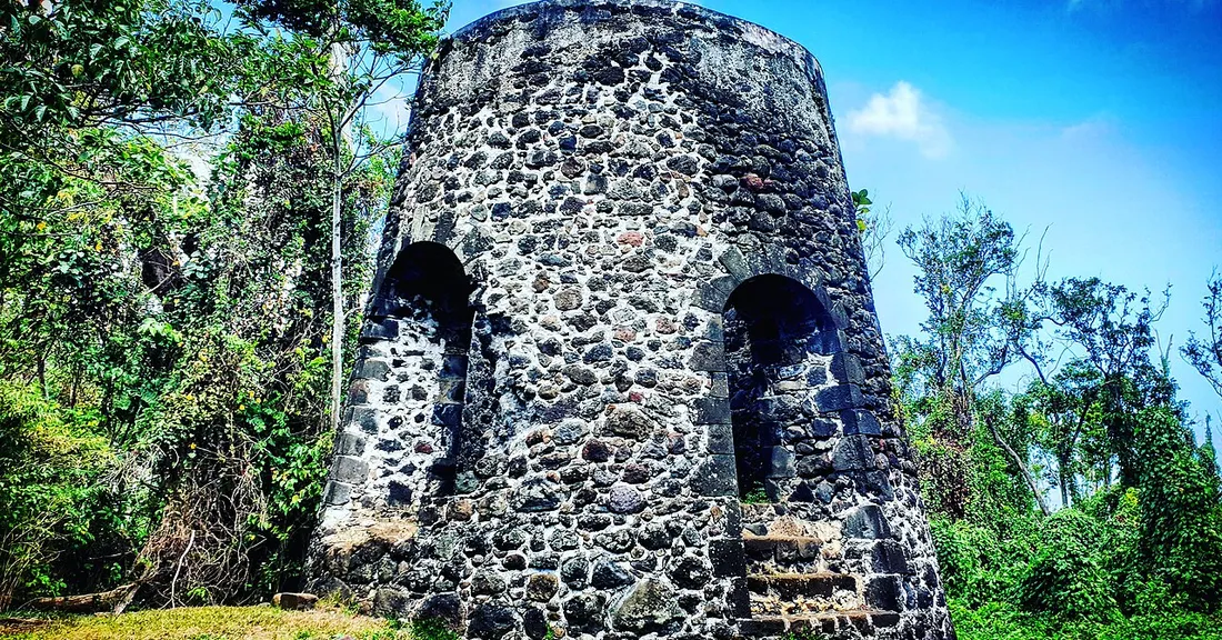 Ruine en pierre d'un ancien moulin à canne à sucre envahi par la végétation en Guadeloupe, héritage de l'époque coloniale