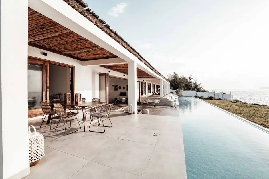 Terrasse couverte d'une villa de location saisonniere tropicale avec coin repas et piscine a debordement face a la mer