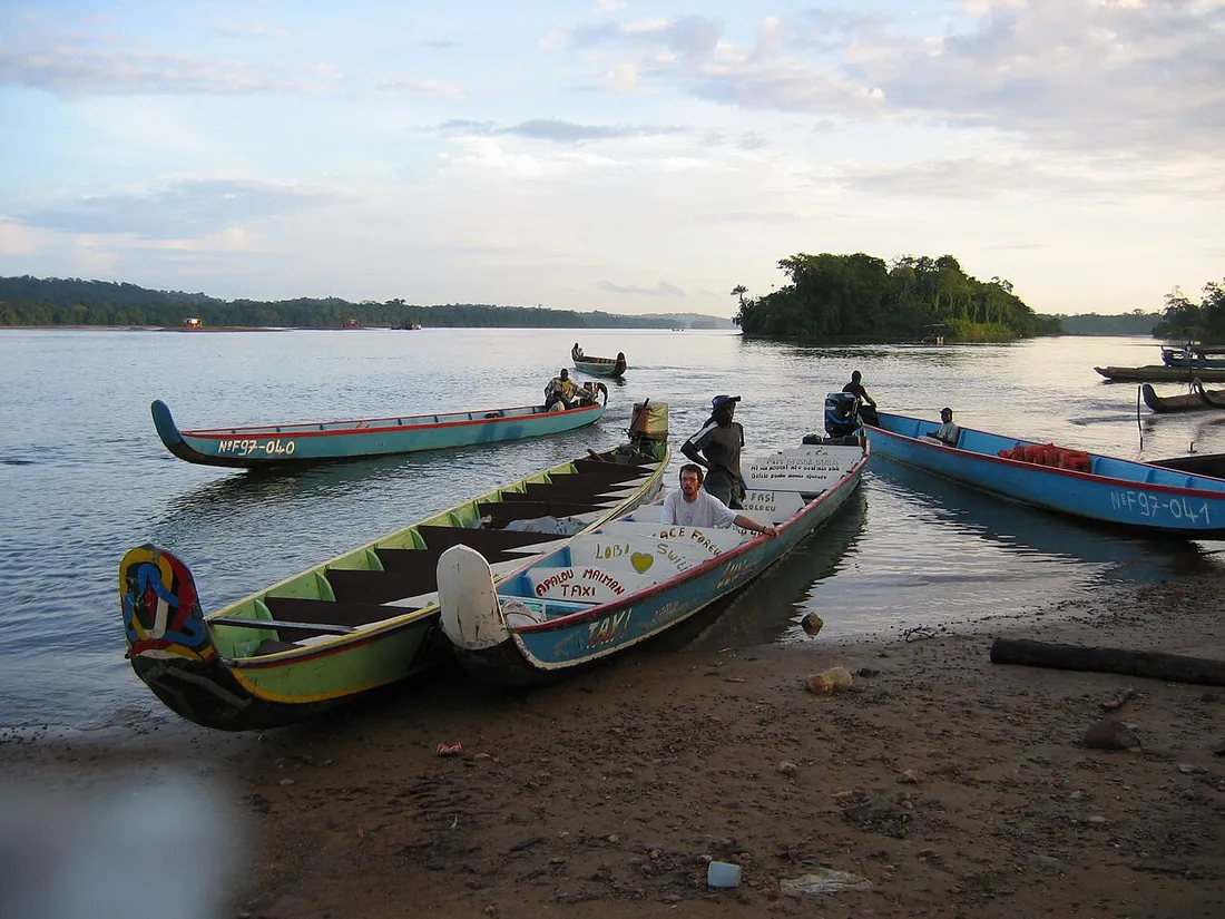 Pirogues-taxis colorees amarrees sur la berge du fleuve Maroni a Apatou, en Guyane, dont une portant l'inscription Apatou Maiman Taxi