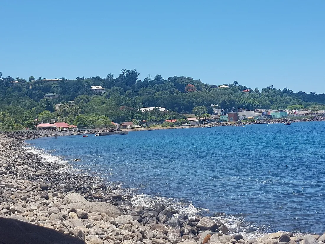 Le bourg côtier de Bouillante en Guadeloupe vu depuis la plage de galets, avec ses maisons en bord de mer adossées à la colline