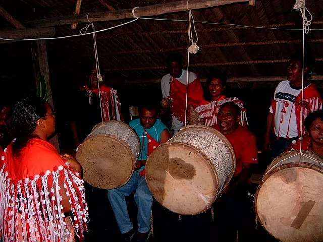 Amérindiens Kali'na en tenue traditionnelle rouge jouant des grands tambours sambura lors d'une fête coutumière