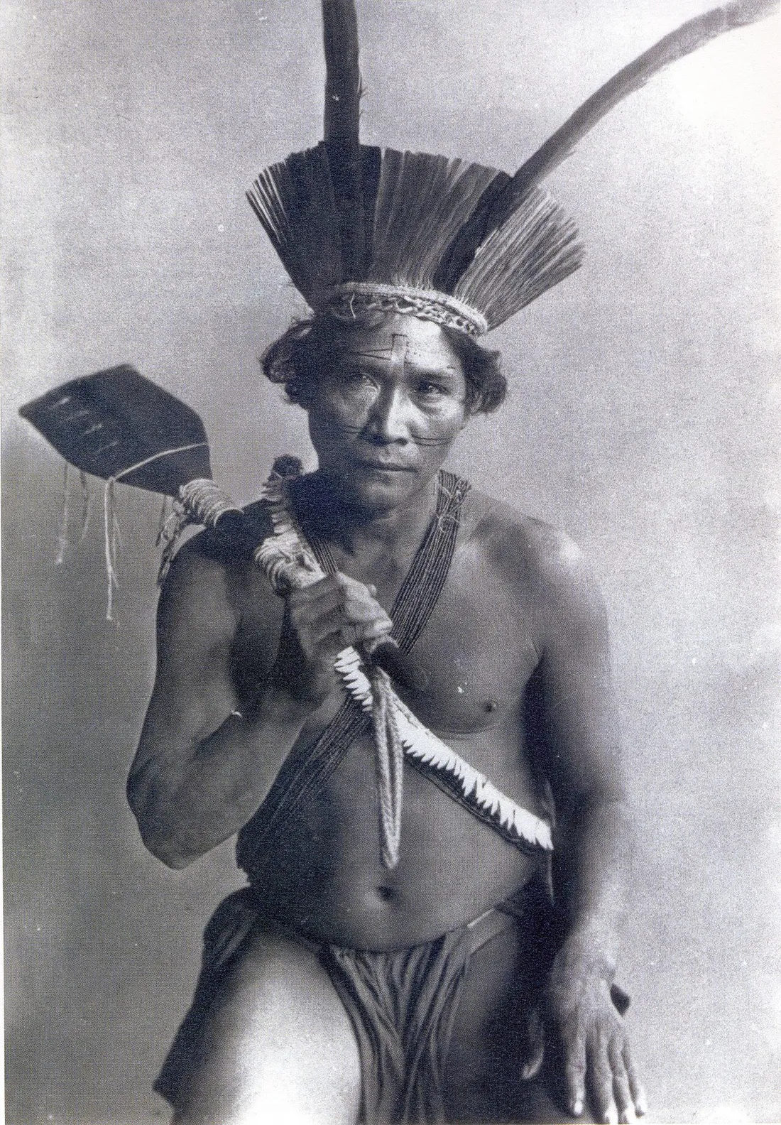 Portrait ancien d'un homme kali'na de Guyane coiffé d'une parure de plumes et tenant un objet cérémoniel