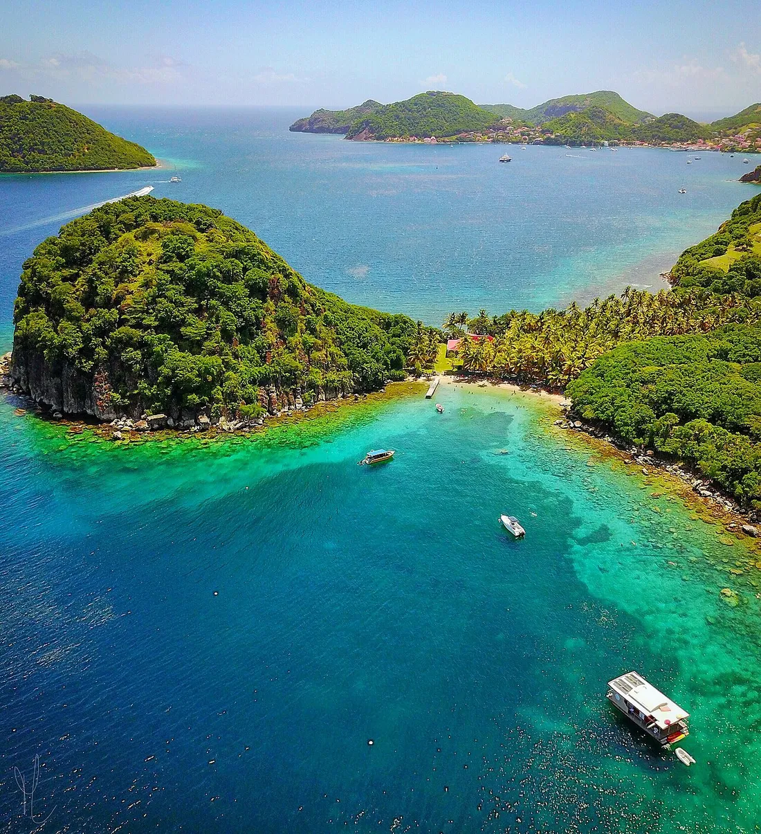Vue aérienne du Pain de Sucre et de la baie turquoise de Terre-de-Haut, aux Saintes (Guadeloupe), avec bateaux mouillés près du rivage