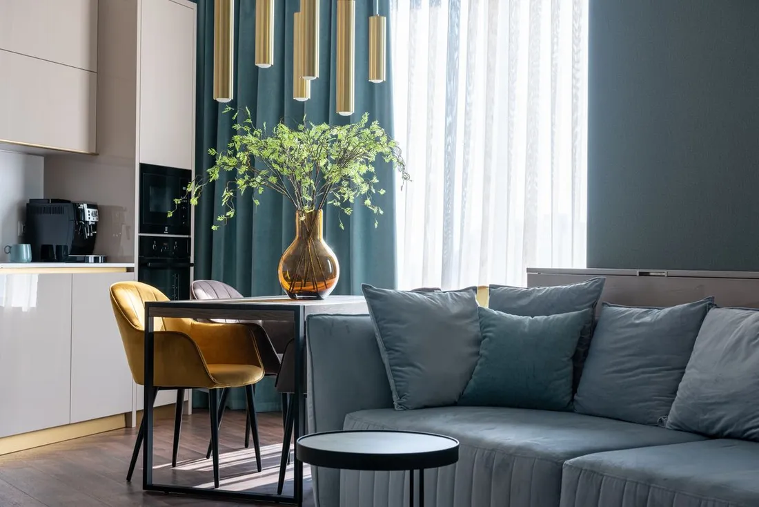 Salon meublé d'un appartement moderne avec canapé, coin repas et cuisine équipée, illustrant un logement loué en meublé