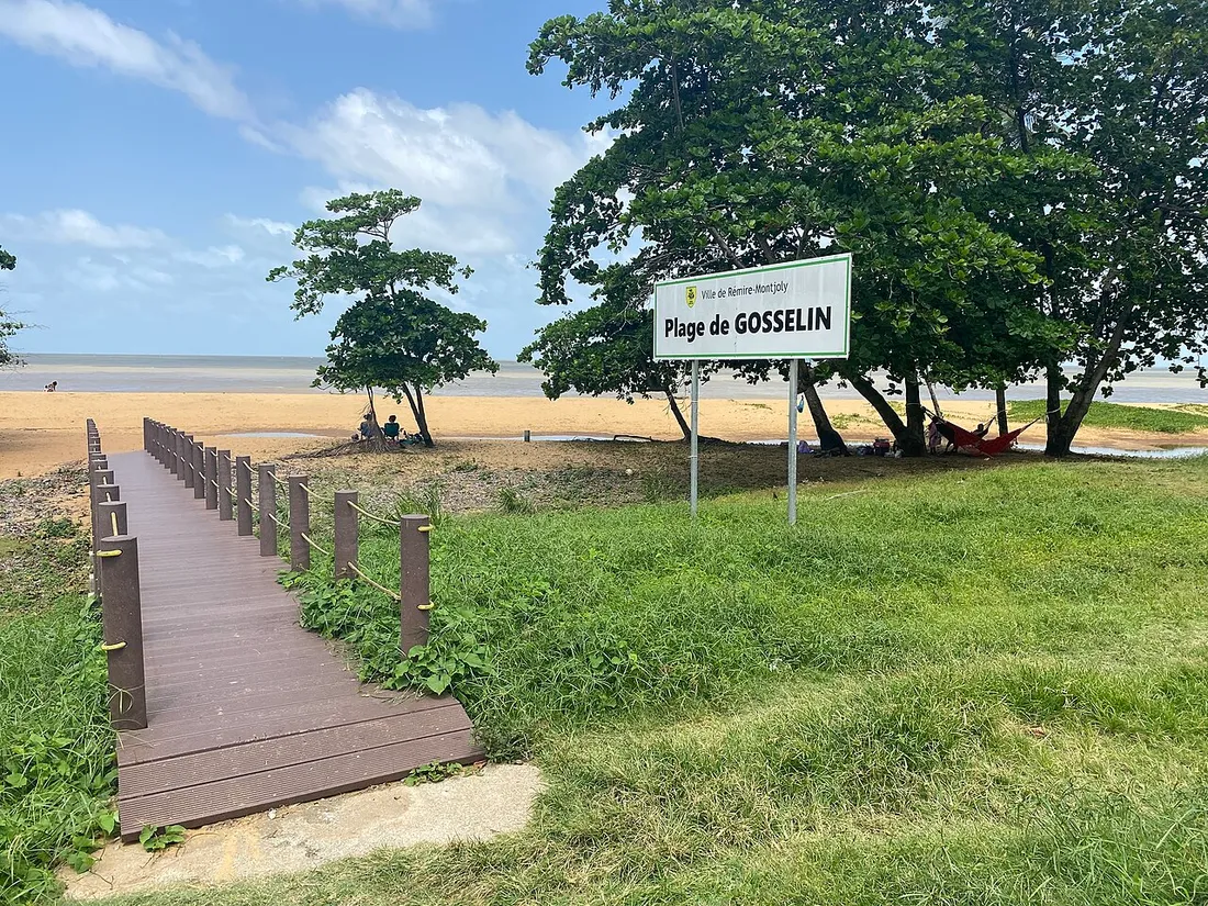 Accès en bois et panneau de la plage de Gosselin à Rémire-Montjoly, hamac sous les arbres au bord de la plage