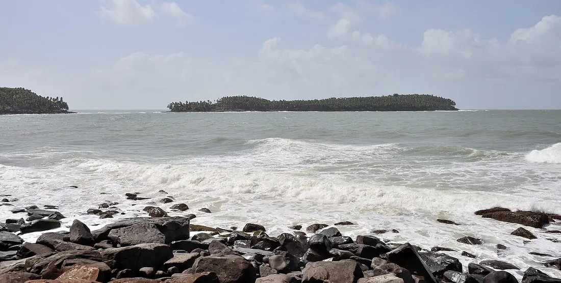 Vue sur les iles du Salut couvertes de cocotiers au large de Kourou, avec vagues et rochers en premier plan