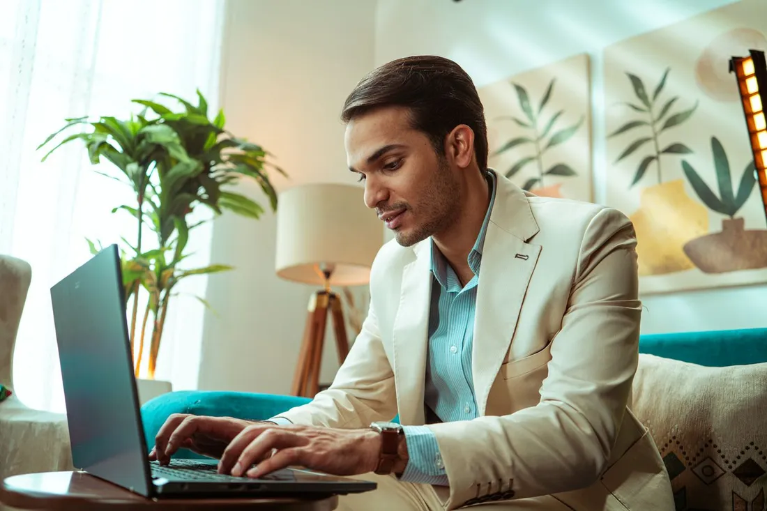 Consultant en costume clair travaillant sur son ordinateur portable dans un logement au decor soigne