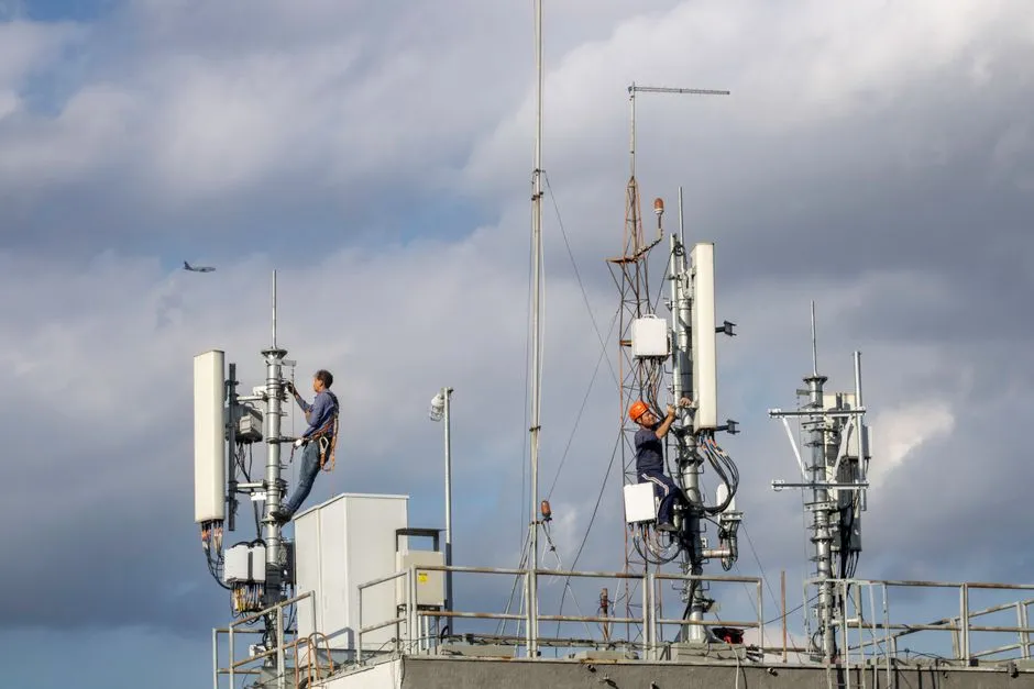 Deux techniciens télécoms harnachés intervenant sur les antennes relais installées en toiture