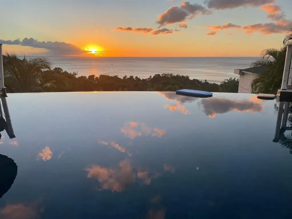 Piscine à débordement dominant la mer au coucher du soleil, à Bouillante en Guadeloupe