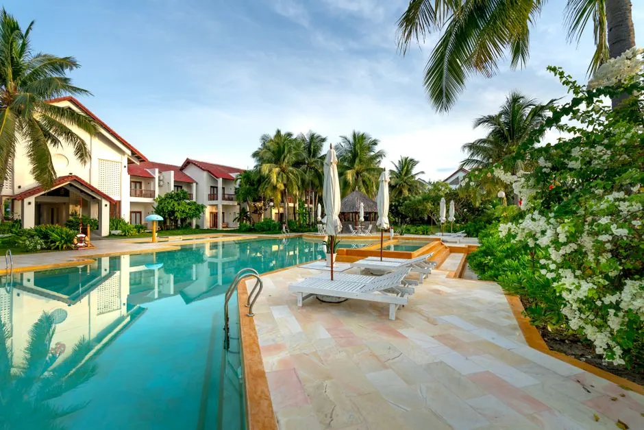 Villas avec grande piscine extérieure, transats et palmiers dans un jardin tropical en bord de Caraïbes