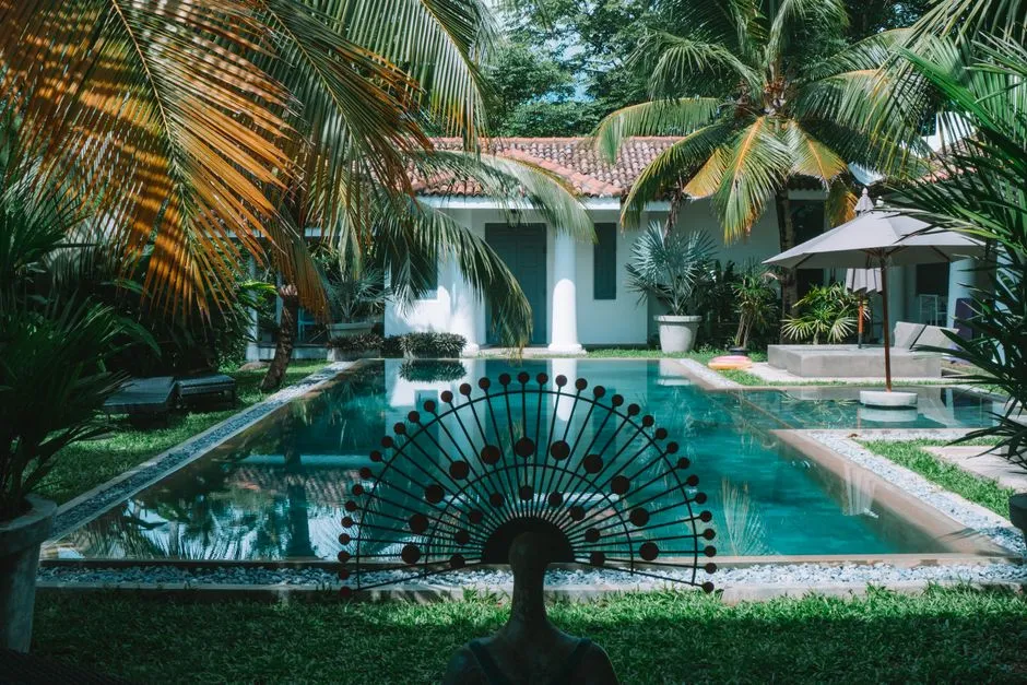 Villa privée avec piscine rectangulaire bordée de pelouse et de palmiers, ambiance intimiste tropicale