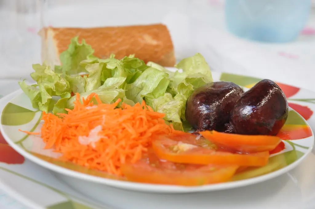Assiette de boudin créole antillais accompagné de salade verte, carottes râpées et tomates