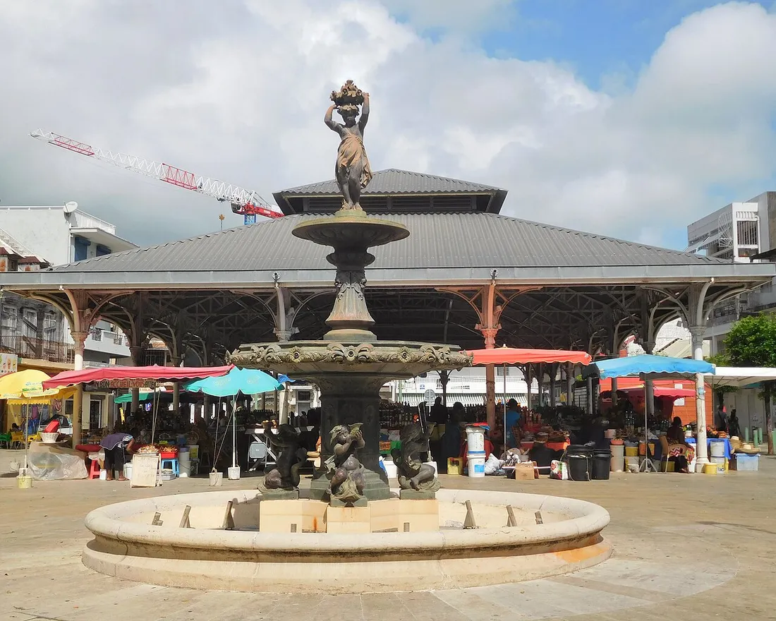 Le marché central de Pointe-à-Pitre en Guadeloupe avec ses étals abrités sous parasols colorés et sa fontaine au premier plan