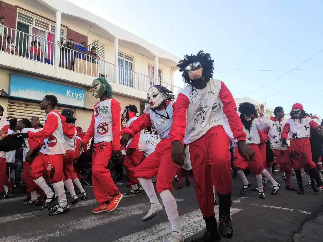 Groupe de Mas a po masques defilant en costumes rouges et blancs dans une rue de Guadeloupe pendant le carnaval