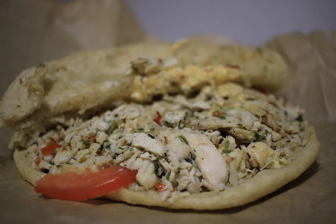 Bokit guadeloupéen ouvert garni de poulet, tomate et persil dans son pain frit doré