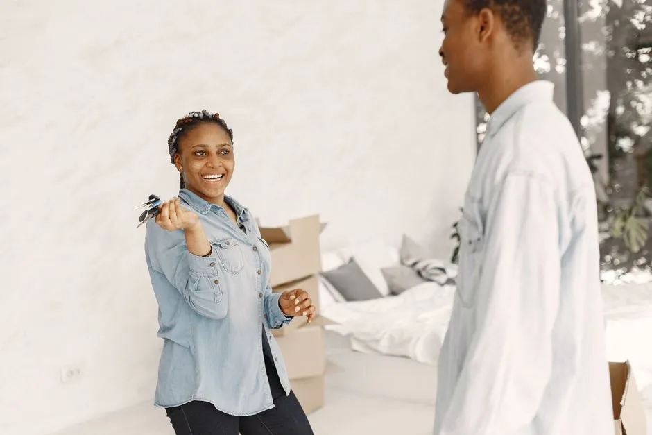 Jeune femme brandissant les clés de son nouvel appartement devant des cartons de déménagement