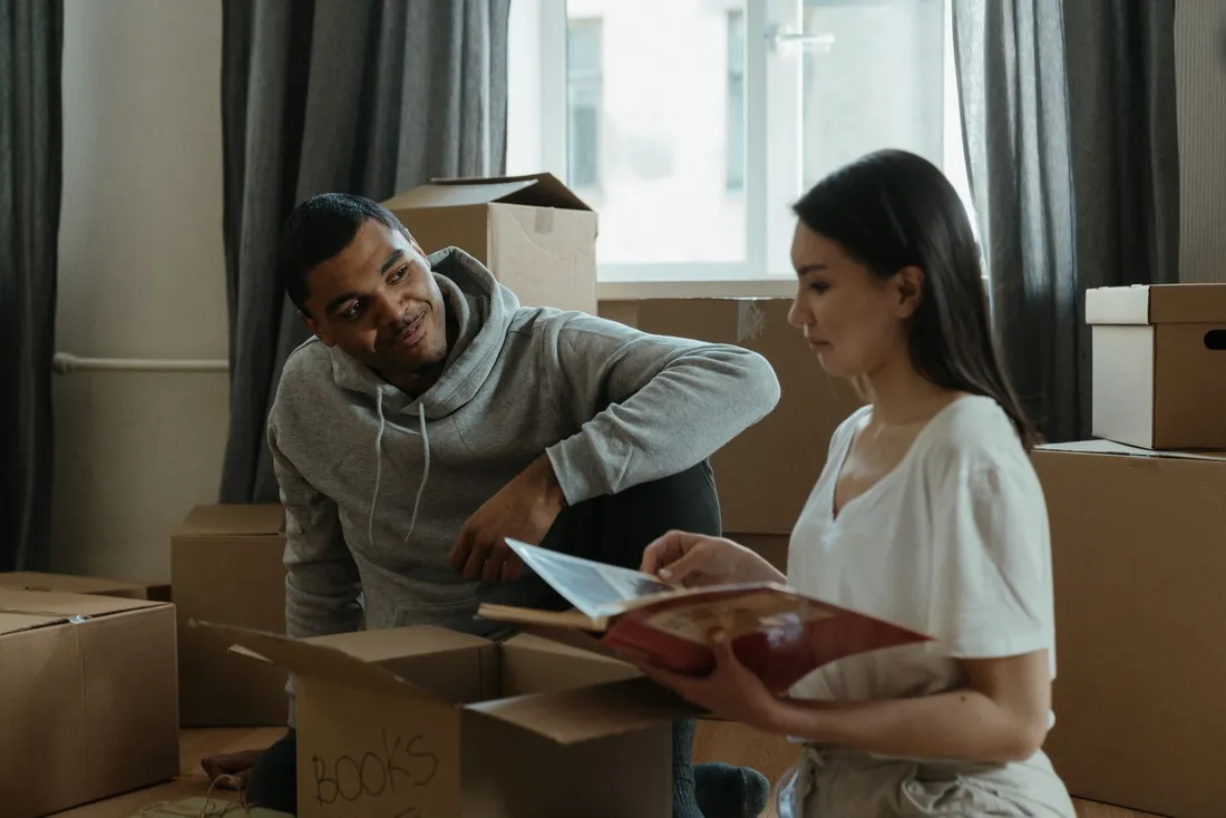 Couple decouvrant son nouveau logement en deballant des cartons de demenagement au sol