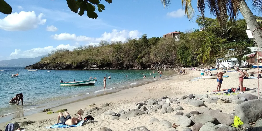 Plage de l'Anse Dufour en Martinique, sable clair, eau turquoise et maisons sur les hauteurs proches du littoral
