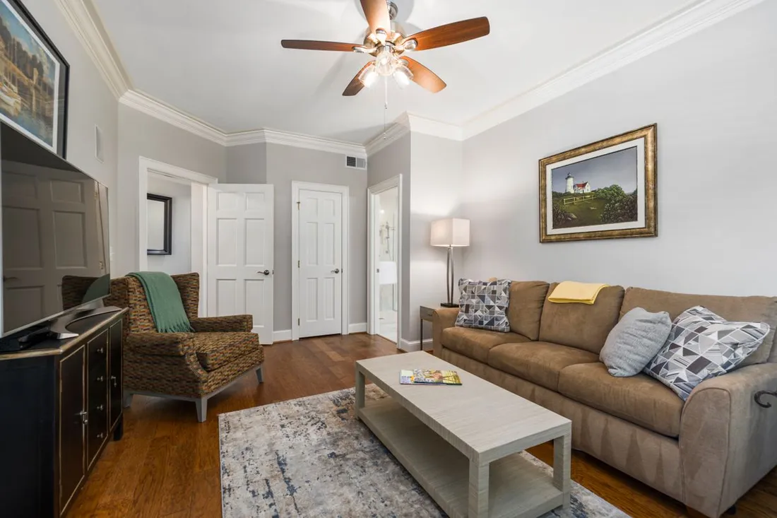 Salon entièrement meublé d'un logement locatif avec canapé, fauteuil, table basse et téléviseur, typique d'une location meublée