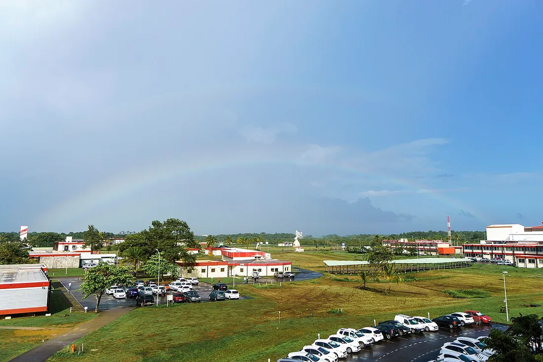 Vue du Centre Spatial Guyanais a Kourou avec ses batiments et une antenne de poursuite, sous un arc-en-ciel