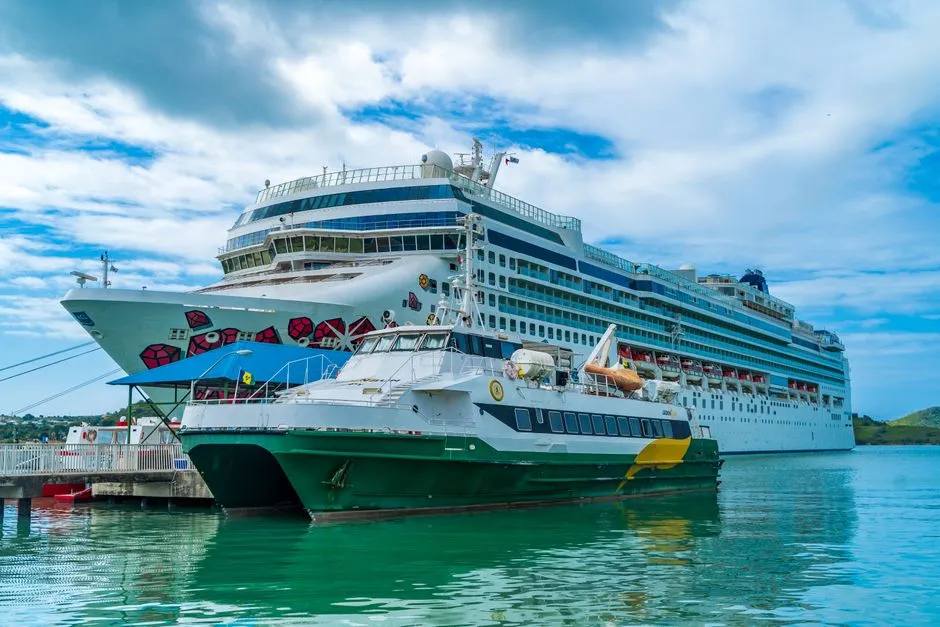 Navette maritime catamaran amarrée à quai à côté d'un grand navire dans un port des Caraïbes