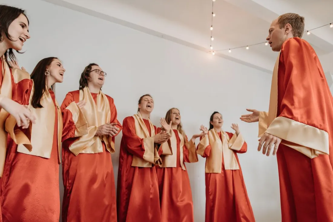 Chorale en robes rouge et or chantant ensemble des cantiques de Noël, image d'illustration du Chanté Nwel