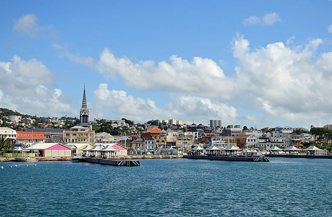 Panorama du front de mer de Fort-de-France en Martinique, avec la baie, les pontons colorés et le clocher de la cathédrale Saint-Louis dominant la ville, destination fréquente des déplacements professionnels outre-mer