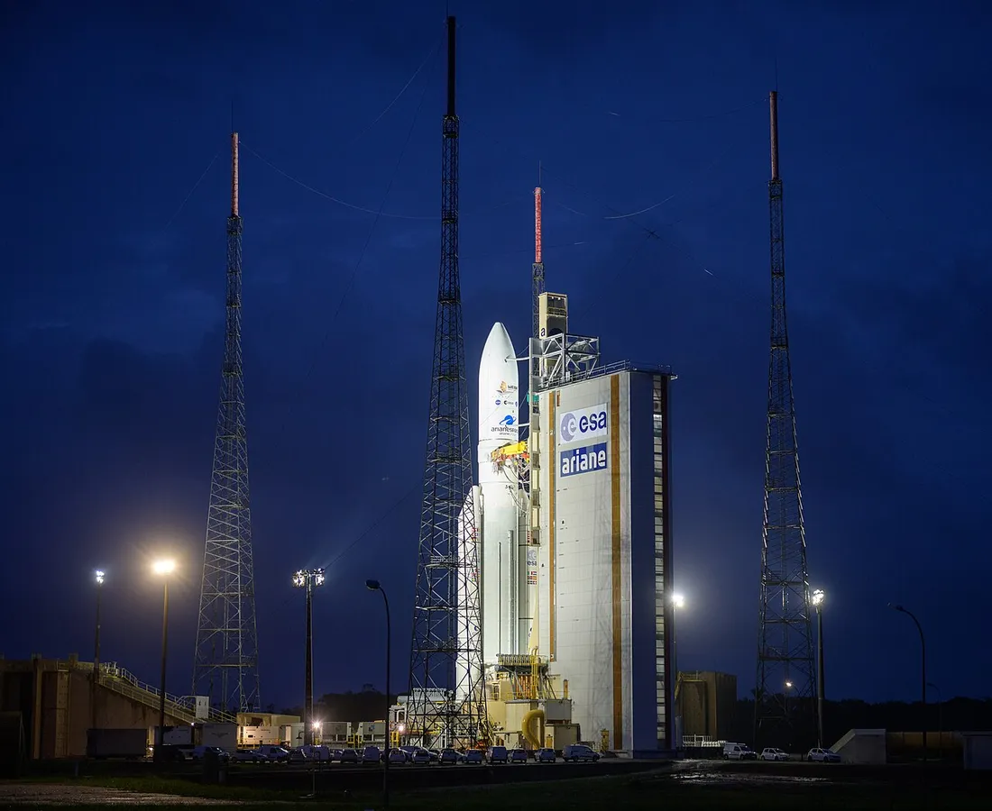 Fusée Ariane 5 dressée sur son pas de tir illuminé du Centre Spatial Guyanais de Kourou, au crépuscule, entourée des tours paratonnerre