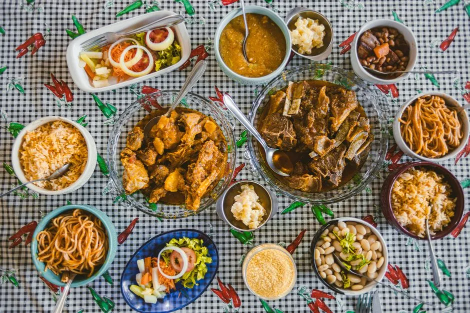 Table garnie de plats bresiliens : viande mijotee, haricots, riz, farofa et accompagnements servis dans des bols