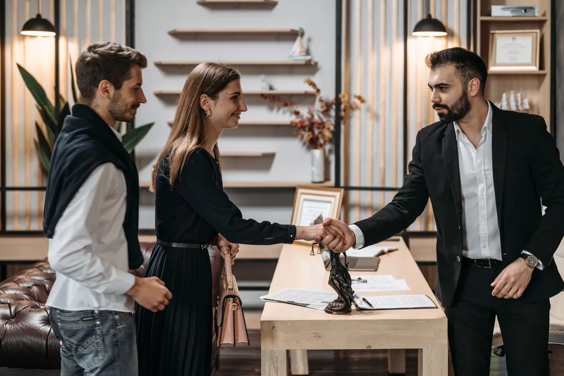 Poignee de main entre un couple de clients et un professionnel de l'hebergement dans un accueil elegant
