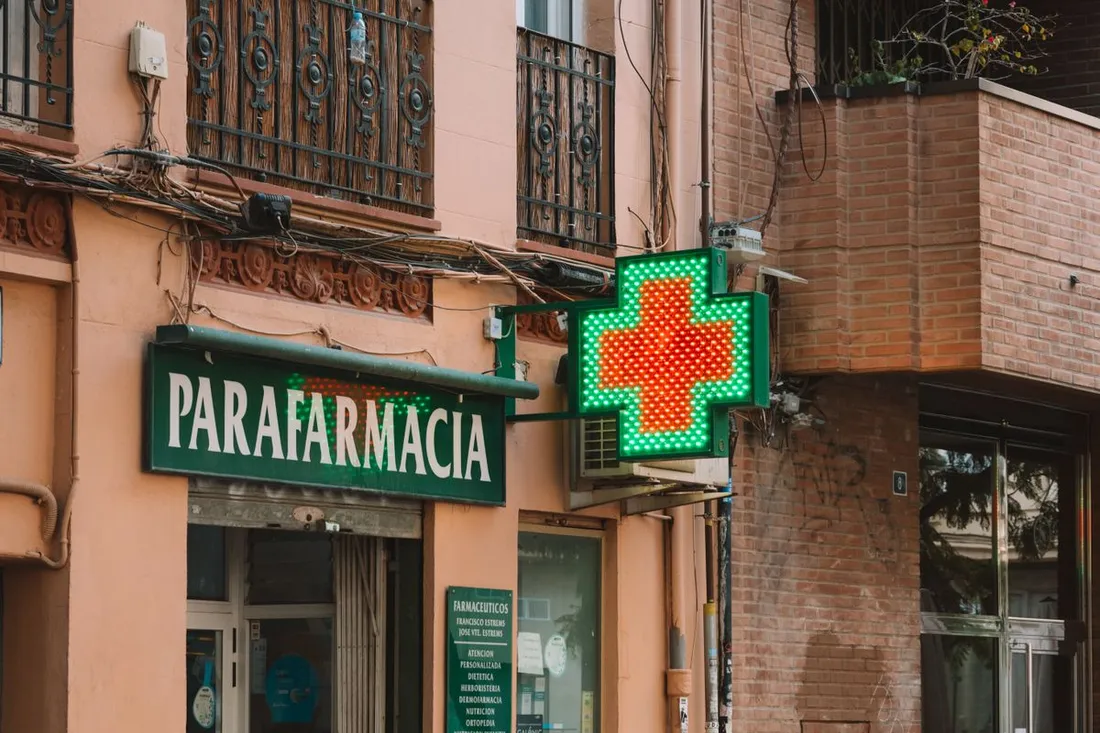 Croix verte lumineuse d'une pharmacie de garde signalant une officine ouverte dans une rue