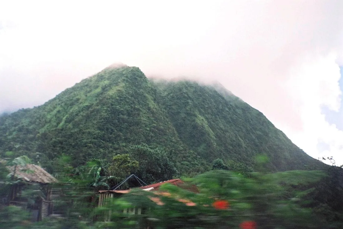 Sommet verdoyant et escarpe d'un piton du massif du Carbet coiffe de nuages en Martinique