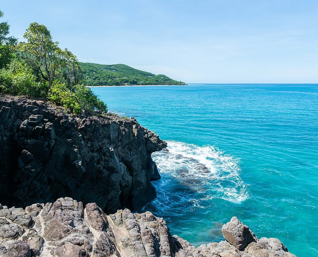 Cote rocheuse pres de la plage de la Perle a Deshaies, en Guadeloupe, ou la houle vient se briser en ecume sur les roches volcaniques