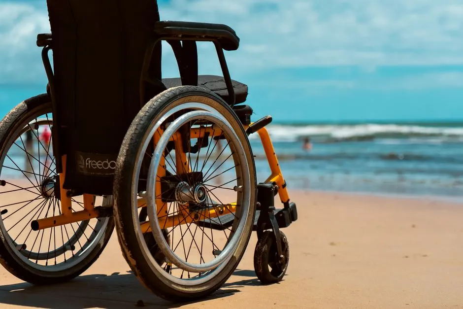 Fauteuil roulant posé sur le sable face à la mer, illustrant l'accessibilité PMR d'une plage