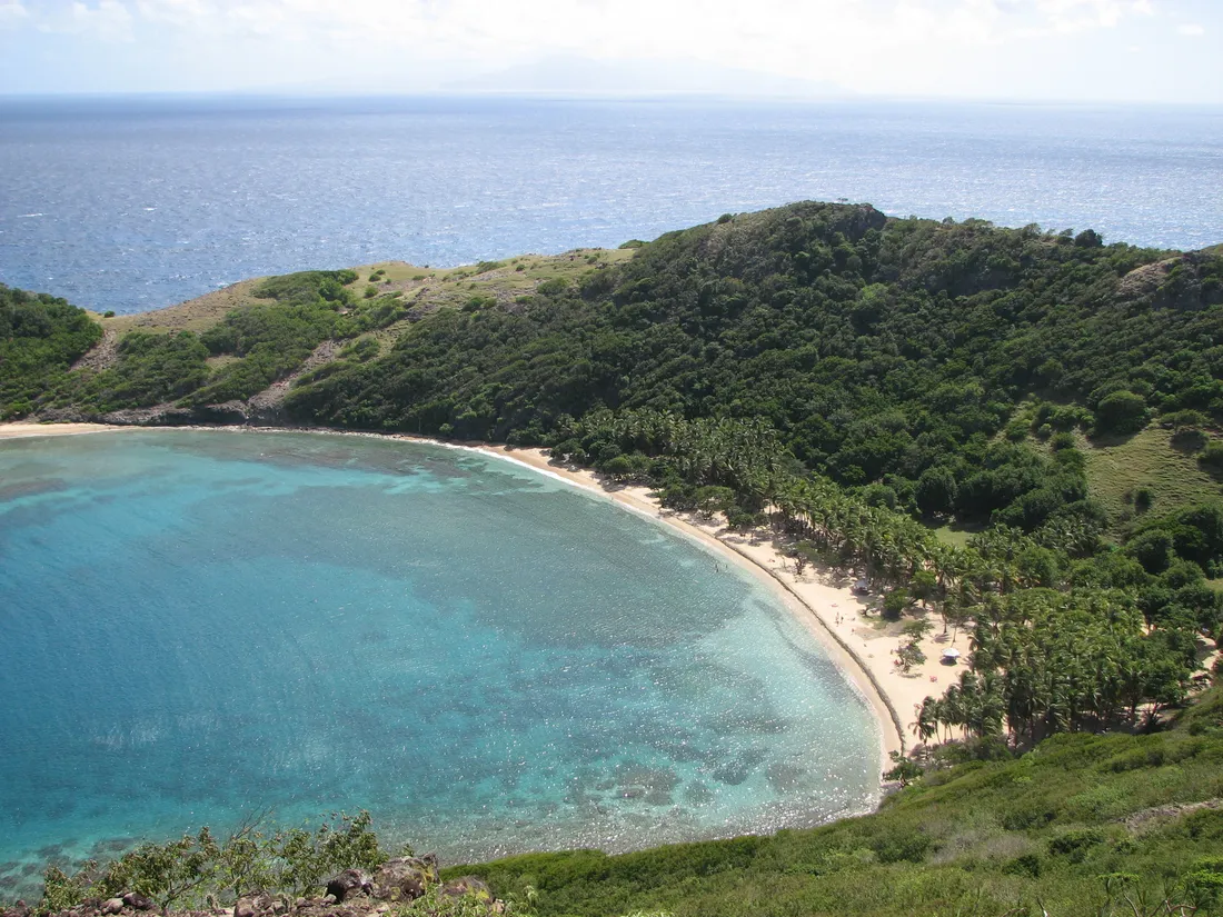 Vue aérienne de la plage de Pompierre à Terre-de-Haut des Saintes, sa baie en arc de cercle bordée de cocotiers et son eau turquoise peu profonde