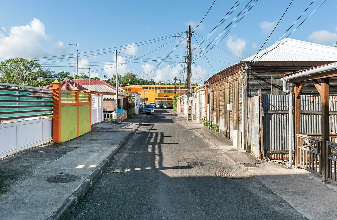 Ruelle résidentielle bordée de maisons créoles à Sainte-Anne, en Guadeloupe, illustrant le marché immobilier local