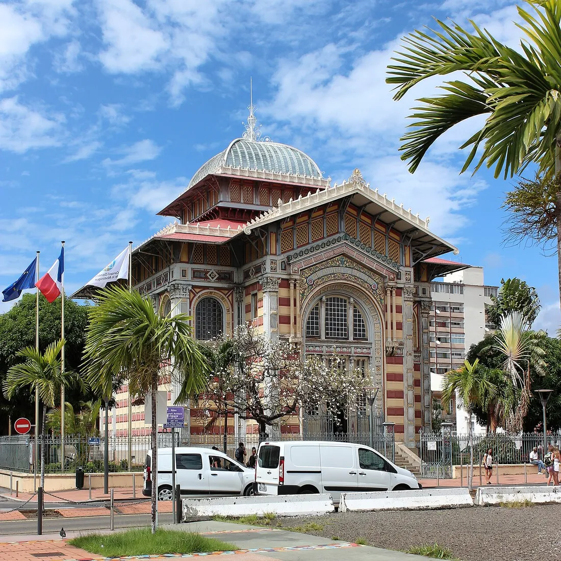 La bibliothèque Schœlcher à Fort-de-France, monument emblématique à l'architecture coloriée bordé de palmiers sous un ciel bleu