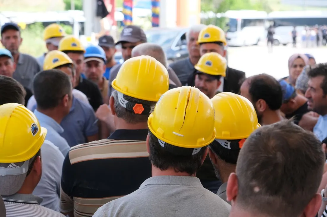 Groupe d'ouvriers portant des casques de chantier jaunes, réunis et vus de dos avant une prise de poste