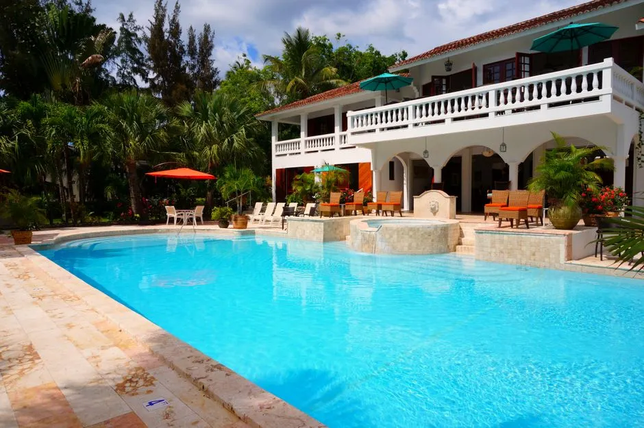 Villa de location de vacances aux Antilles avec grande piscine, terrasse et transats, illustrant un meublé touristique de loueur en Guadeloupe