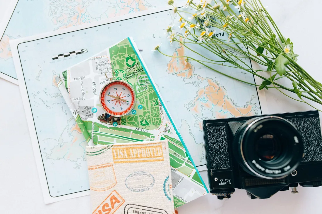 Cartes de voyage, boussole et appareil photo posés sur une table