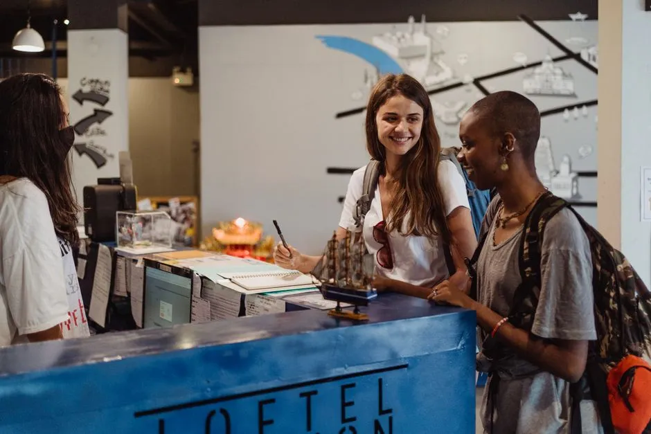 Groupe de voyageurs avec sacs à dos accueillis au comptoir d'un hébergement lors d'une arrivée collective