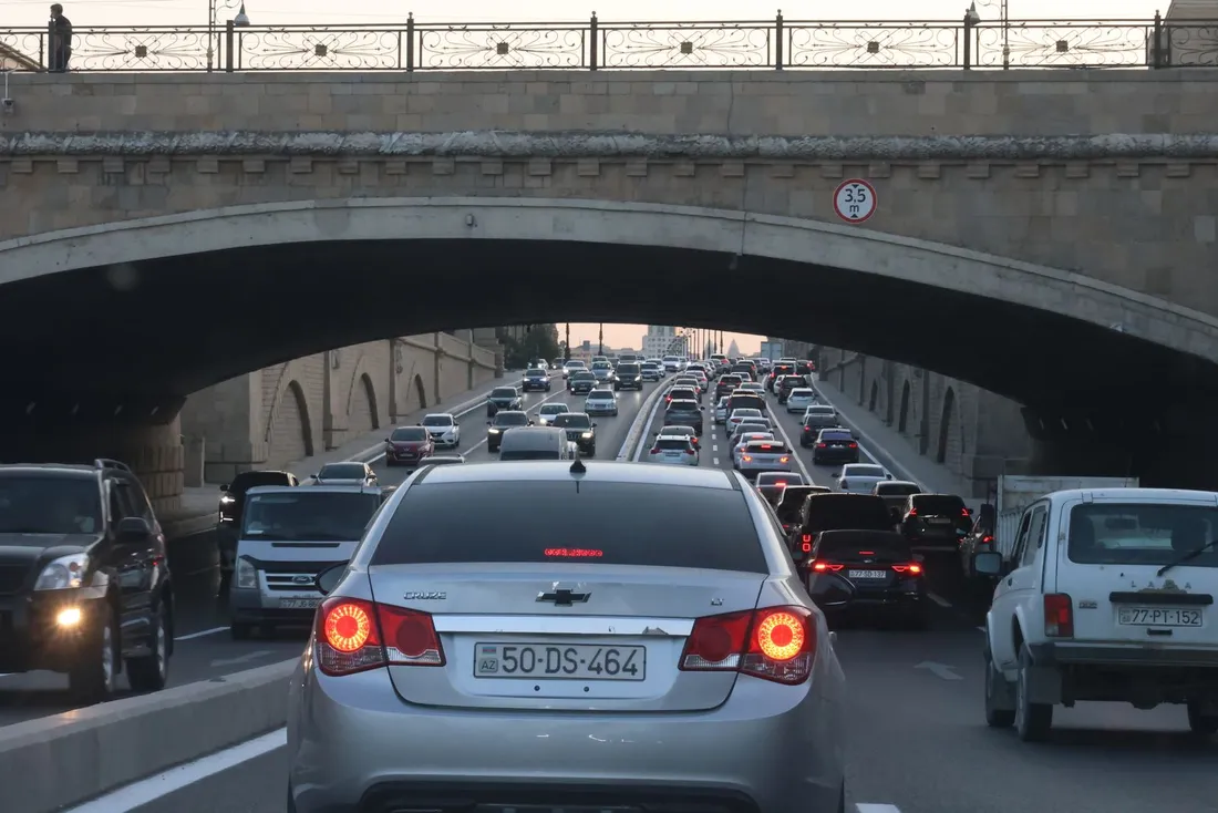 File de voitures à l'arrêt sur deux voies, à l'approche d'un pont de pierre franchi par la circulation