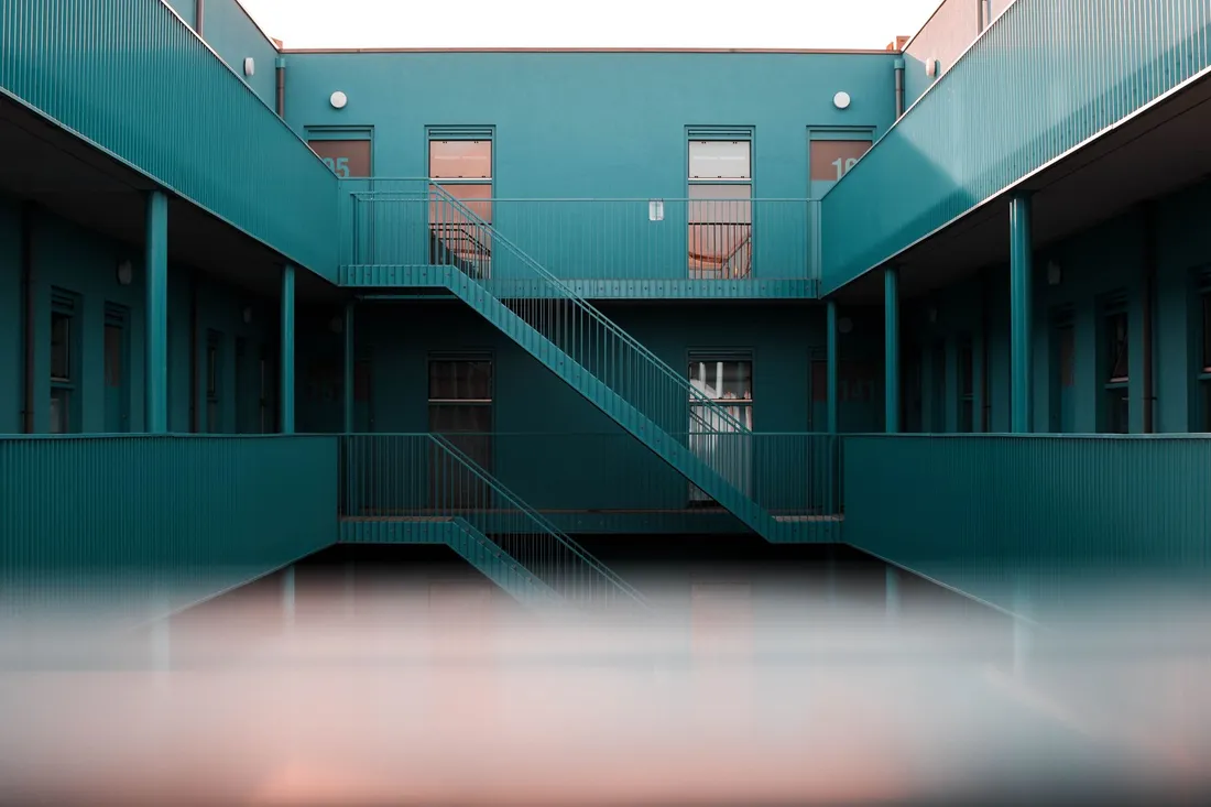 Coursives extérieures et escalier métallique desservant les logements d'une résidence collective, vus depuis la cour