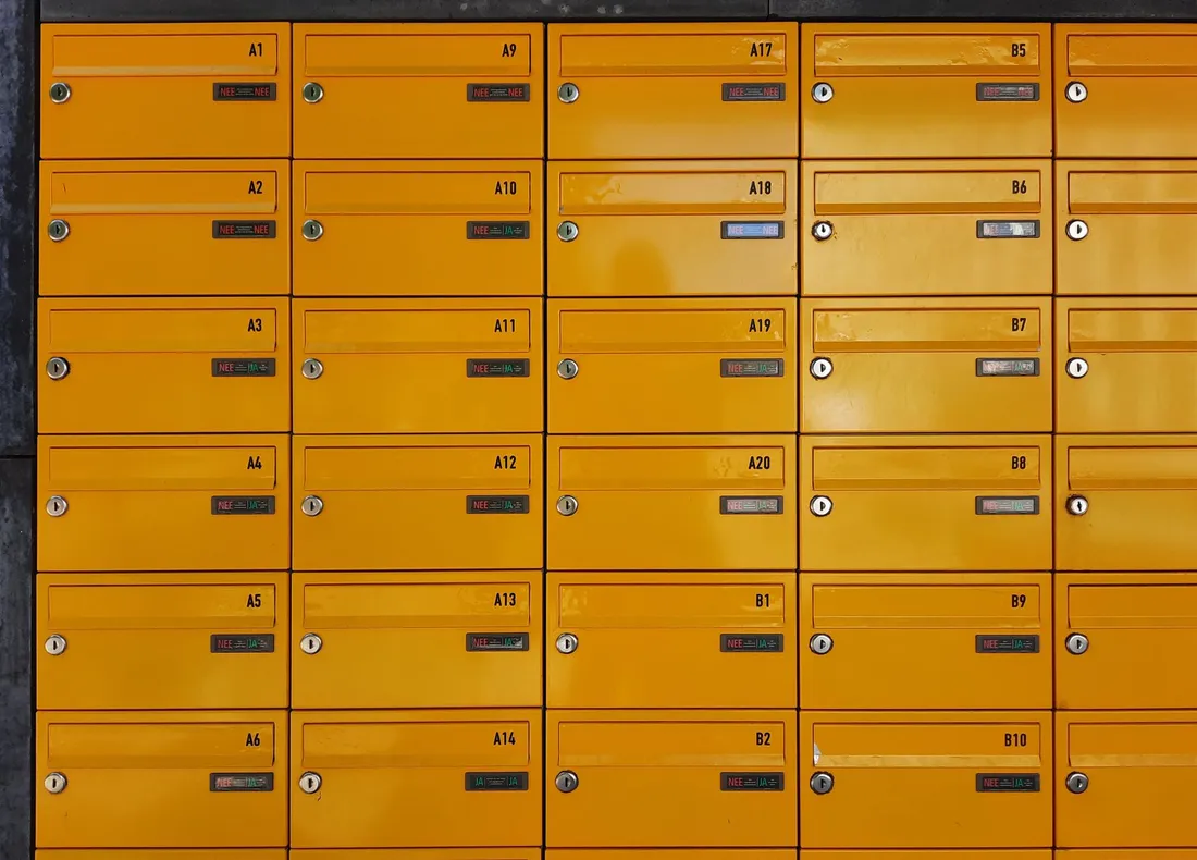 Mur de boîtes aux lettres jaunes numérotées A1 à B10 dans le hall d'un immeuble d'habitation